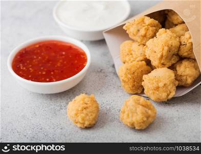 Crunchy southern chicken popcorn bites in paper container for fast food meals on light background. Macro