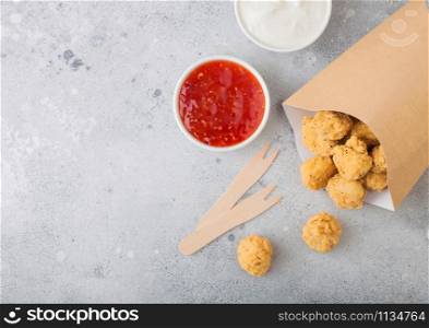 Crunchy southern chicken popcorn bites in paper container for fast food meals on light background. Top view