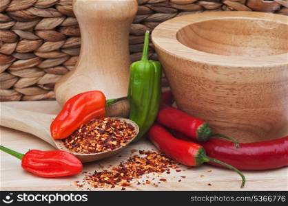 Crushed and whole chilli peppers with wooden utensils in kitchen setting