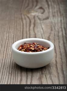 Crushed Chillies In A White Dish, On A Wooden Kitchen Table
