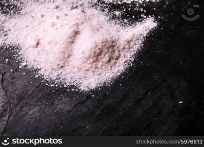 Crushed pink Himalayan salt on slate background. Pile Himalayan salt