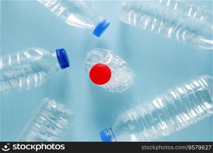 Crushed plastic water bottles with blue caps standing around crushed plastic water bottle with red cap on blue background