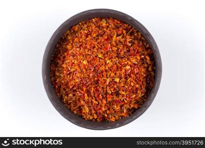 Crushed red chili pepper in stone bowl on white background