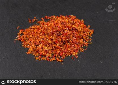 Crushed red chili pepper on dark stone
