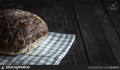 Crusty brown bread on a green towel. Close up with delicious homemade bakery products on a rustic black table