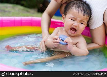 crying baby carried by mother enjoying in the Inflatable pool