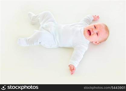 Crying four month old baby girl laying on back&#xA;