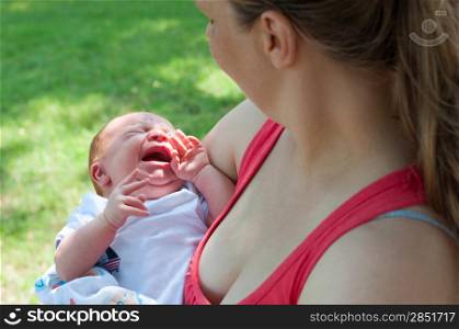 Crying Newborn Baby and Mother From Behind Outdoors