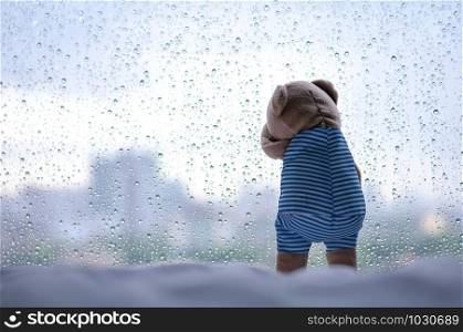 Crying Teddy Bear at the window in rainy day.