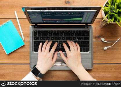 cryptocurrency, business and technology concept - close up of woman hands typing on laptop computer with diagram charts on screen. hands with cryptocurrency on laptop screen