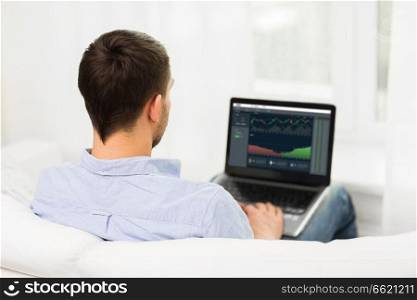 cryptocurrency, data analysis and technology concept - close up of man typing on laptop computer with diagram charts on screen. man with charts on laptop screen at home