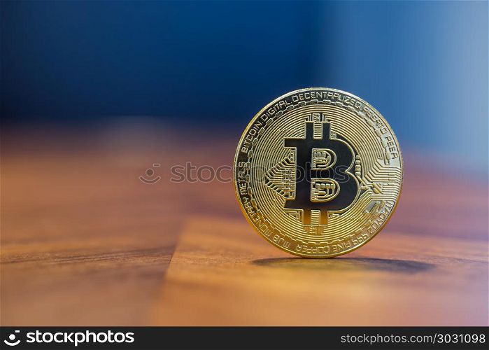 Cryptocurrency electronic sign Bitcoin with background copy spac. Cryptocurrency symbol electronic sign, focus on gold metal Bitcoin stack on wooden table, blur dark blue wall background copy space. Concept of transfer or exchange digital money through blockchain.