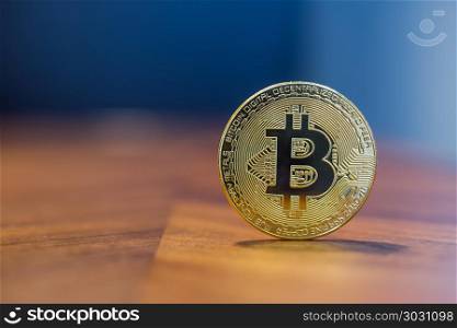 Cryptocurrency electronic sign Bitcoin with background copy spac. Cryptocurrency symbol electronic sign, focus on gold metal Bitcoin stack on wooden table, blur dark blue wall background copy space. Concept of transfer or exchange digital money through blockchain.