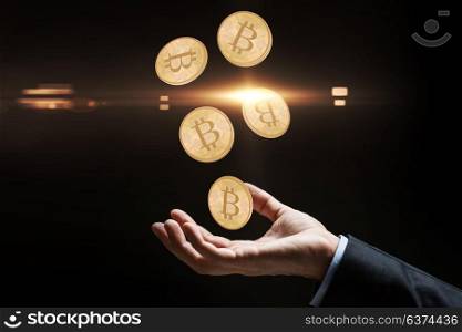 cryptocurrency, finance and business concept - close up of businessman hand with bitcoins over black background. close up of businessman hand with bitcoins