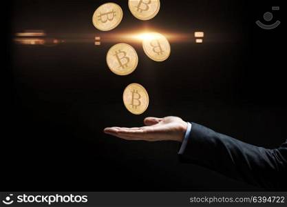 cryptocurrency, finance and business concept - close up of businessman hand with bitcoins over black background. close up of businessman hand with bitcoins