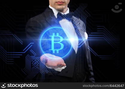 cryptocurrency, finance and business concept - close up of magician hand with virtual bitcoin symbol hologram over black background. close up of magician with bitcoin symbol