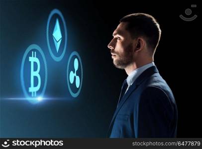 cryptocurrency, financial technology and business concept - buisnessman looking at virtual bitcoin, ethereum and ripple icons over dark background. buisnessman looking at cryptocurrency icons. buisnessman looking at cryptocurrency icons