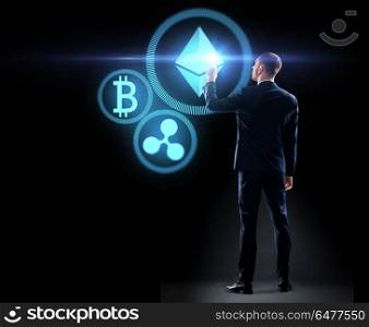 cryptocurrency, financial technology and business concept - buisnessman with virtual bitcoin, ethereum and ripple icons over black background. buisnessman with cryptocurrency holograms. buisnessman with cryptocurrency holograms