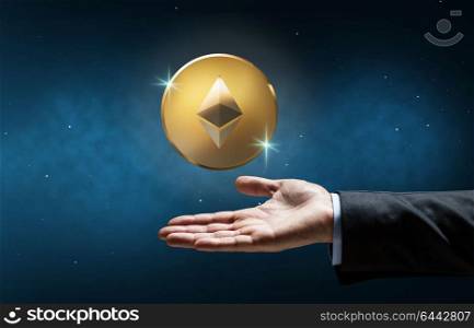 cryptocurrency, financial technology and business concept - businessman hand with golden ether coin over space background. businessman hand with etherum over space