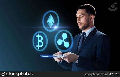 cryptocurrency, financial technology and business concept -businessman with transparent tablet pc computer and virtual bitcoin, ethereum and ripple holograms over dark background. businessman with tablet pc and cryptocurrency. businessman with tablet pc and cryptocurrency