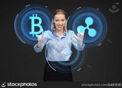 cryptocurrency, financial technology and business concept - smiling businesswoman working with virtual bitcoin, ethereum and ripple hologram over dark background. businesswoman with cryptocurrency holograms. businesswoman with cryptocurrency holograms