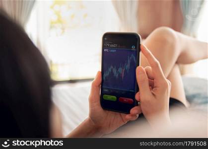 Cryptocurrency Investment Concept. Person Using Mobile Phone on Bed at Home to Buy and Sell Bitcoin via Online Exchange Platform. Blockchain,Fintech Technology. Innovation of Financial Investment