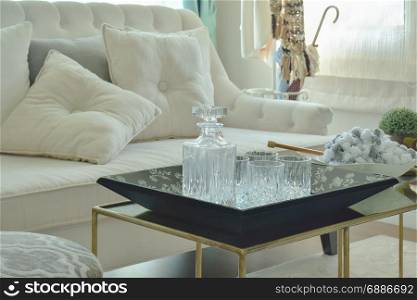 Crystal bottle and glasses on table with beige sofa in living room