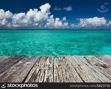 Crystal clear turquoise water and old wooden pier at tropical maldivian beach