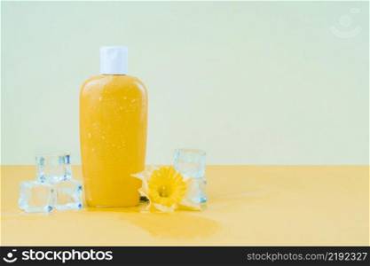 crystal ice cubes with daffodil flower yellow sunscreen lotion bottle against green backdrop
