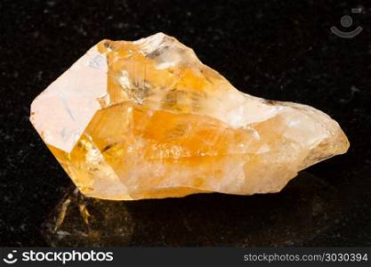 crystal of Citrine gemstone on black. macro shooting of natural rock specimen - crystal of Citrine (yellow quartz) gemstone on black granite background from Brazil