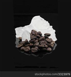 crystal sugar and coffee beans over black reflective surface background
