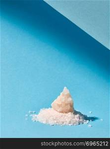 Crystals of natural sugar of heap for cooking and decoration cakes on a light pastel blue paper with copy space.. Sweet sugar heap and big crystal for decoration cake isolated on a blue background with shadows.