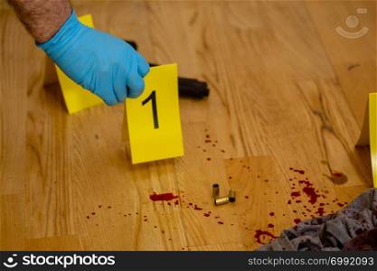 CSI forensices investigator puts marker down by bullets at crime scene