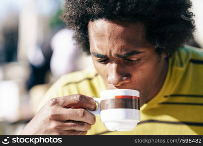 Cuban Black Man enjoying coffee in cafe while sitting at the table outdoors on his trip to Granada, Spain.. Black man enjoying coffee in cafe while sitting at the table outdoors