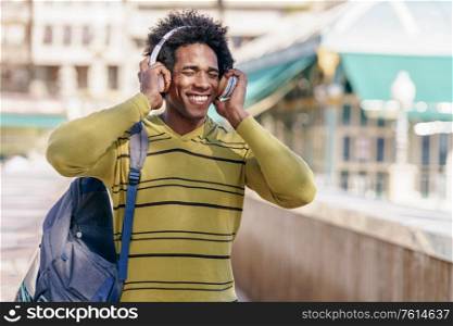 Cuban Black man with afro hair listening to music with wireless headphones sightseeing in Granada, Andalusia, Spain.. Black man listening to music with wireless headphones sightseeing in Granada