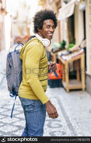 Cuban Black man with afro hair with wireless headphones sightseeing in Granada, Andalusia, Spain.. Black man with wireless headphones sightseeing in Granada
