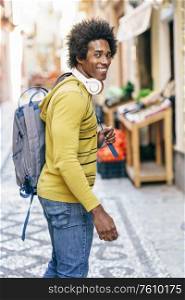 Cuban Black man with afro hair with wireless headphones sightseeing in Granada, Andalusia, Spain.. Black man with wireless headphones sightseeing in Granada