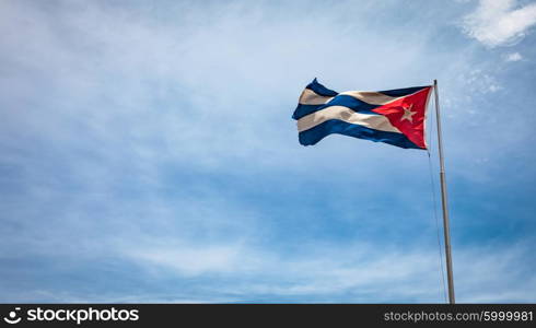 Cuban flag flying in the wind on a backdrop of blue sky. National symbol.