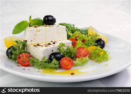 Cubes of feta cheese in oil with spices, cherry tomatoes and olives