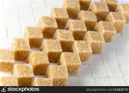 Cubes of not refined reed sugar lie on pieces of white sugar