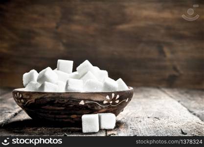 Cubes of sugar in a bowl. On a wooden background. Cubes of sugar in a bowl.