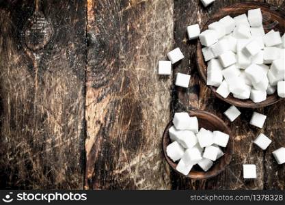 Cubes of sugar in a bowl. On a wooden background. Cubes of sugar in a bowl.