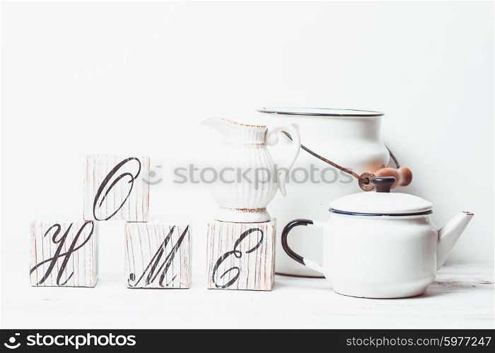 Cubes with inscription home, white teapot and jug on the wooden floor