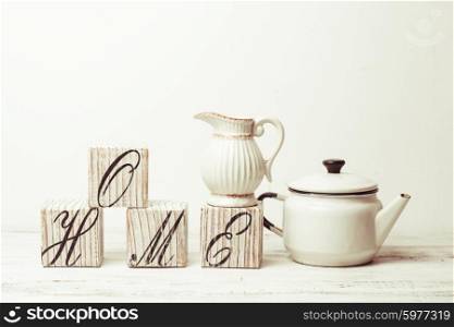 Cubes with inscription home, white teapot and jug on the wooden floor