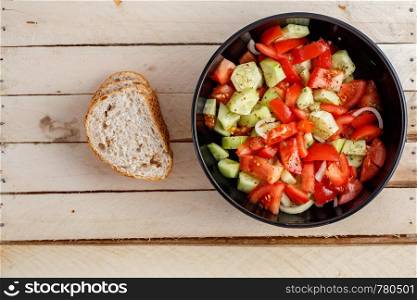 cucumber and tomato salad in black plate on wooden background