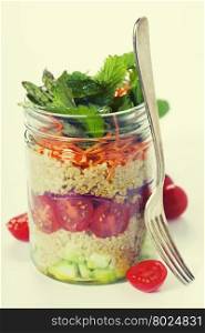 Cucumber, quinoa, tomato, onion, carrot and mint salad in a jar over white