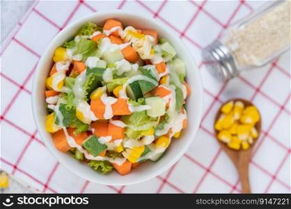 Cucumber salad, corn, carrot and lettuce in a white cup. top view.