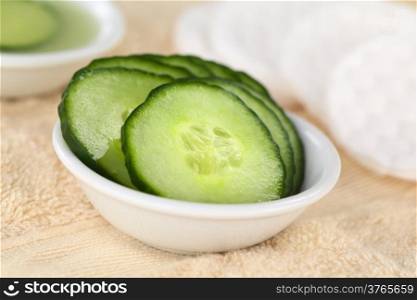 Cucumber slices used as natural moisturizer pads for the eyes in a bowl on towel (Selective Focus, Focus on the middle of the first cucumber slice)