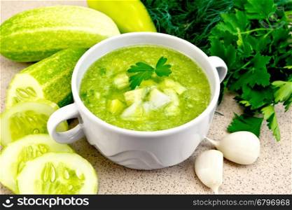 Cucumber soup with green peppers and garlic in a bowl, parsley on a background of a granite table