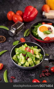 Cucumber stir-fried with tomatoes and red beans in a frying pan with green peas Pepper seeds on black cement.